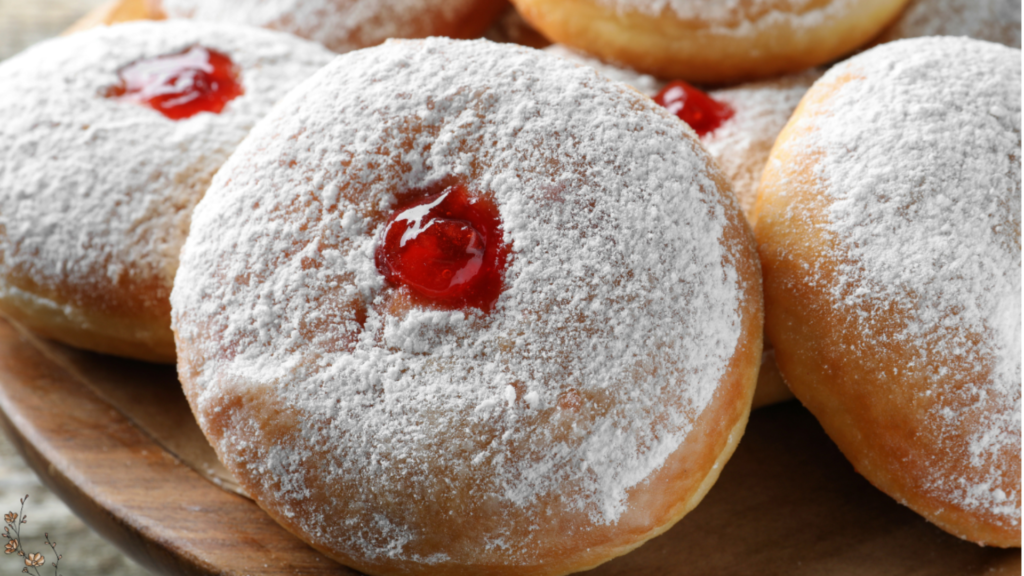 A of French Jelly Filled Beignet recipe arranged and dusted with powdered sugar. A sprinkle of flour on the table adds texture to the shot