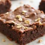 A close-up of a single protein brownies topped with peanuts